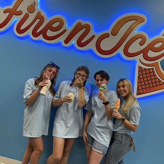 Fire n Ice employees enjoying ice cream, sundaes and shakes at the Fire n Ice dining room beside a Fire N Ice logo on the wall.