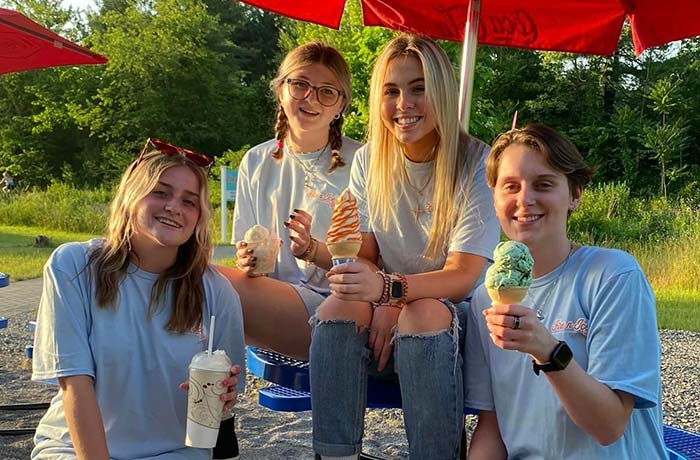 Fire n Ice Murrysville, PA employees anjoying hand scooped ice cream cones and Flavor Burst soft serve ice cream on a picnic table.